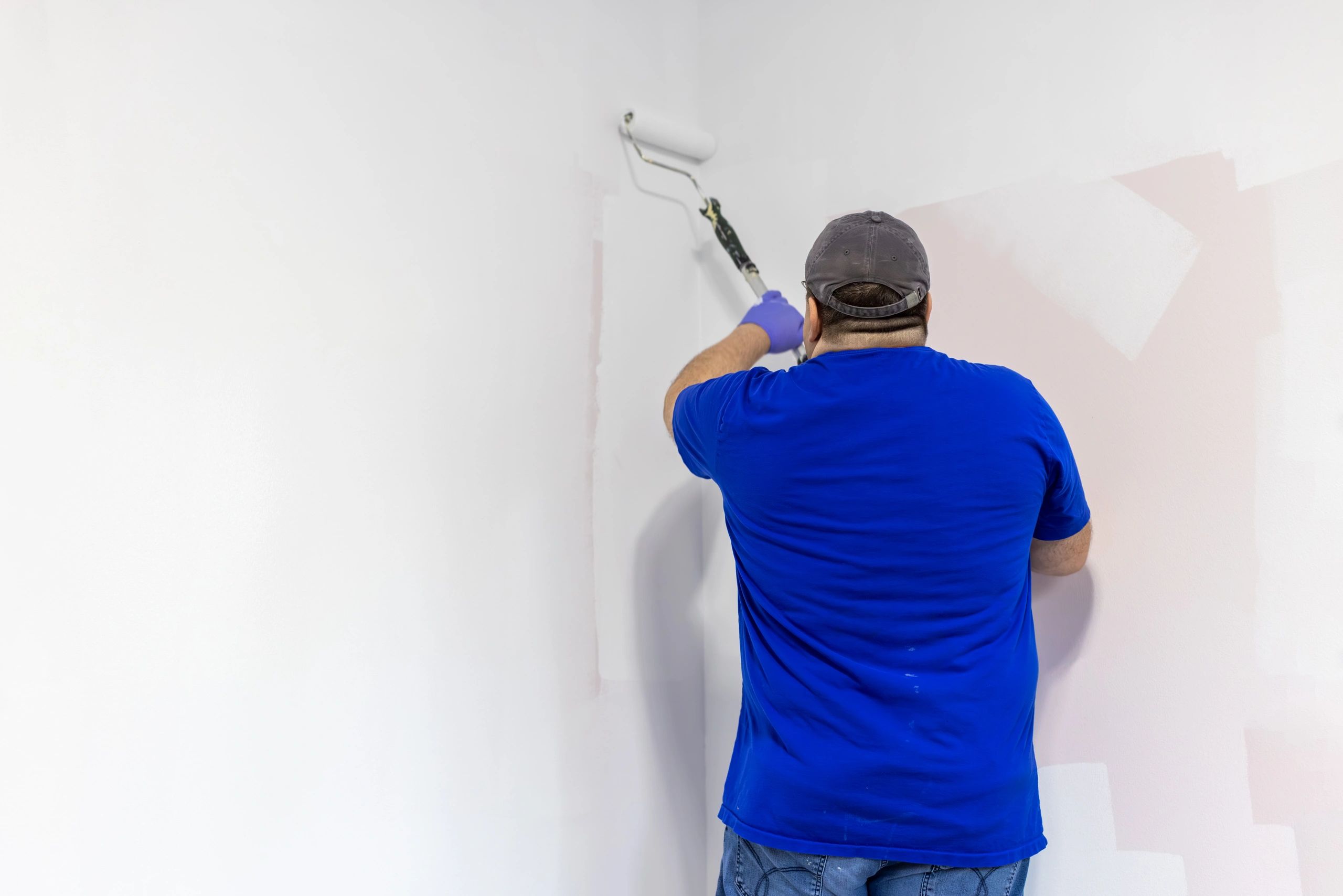 Applying primer with a paint roller on a wall
