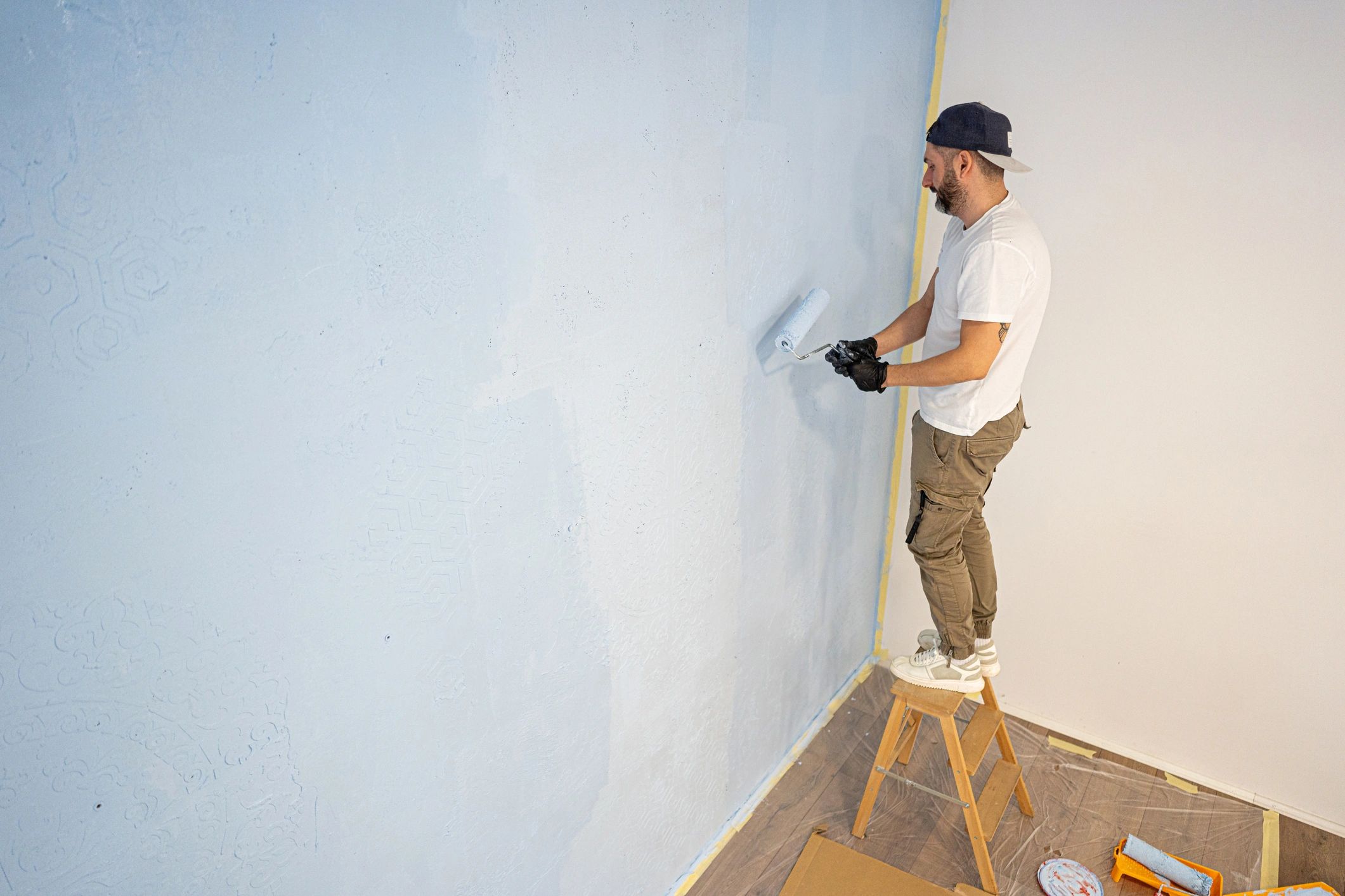 Painter rolling light blue paint on an interior wall