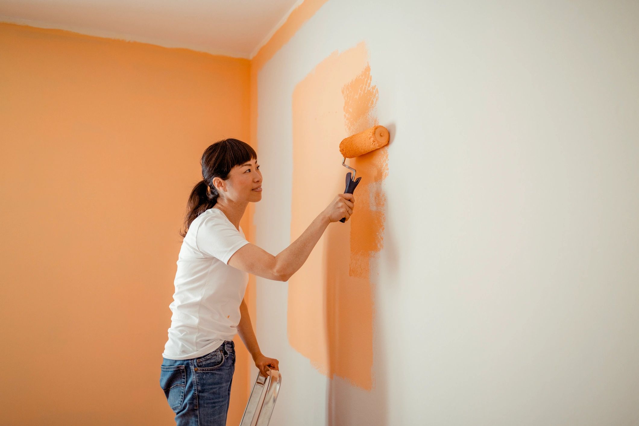 Painter using a roller on an interior wall during a renovation