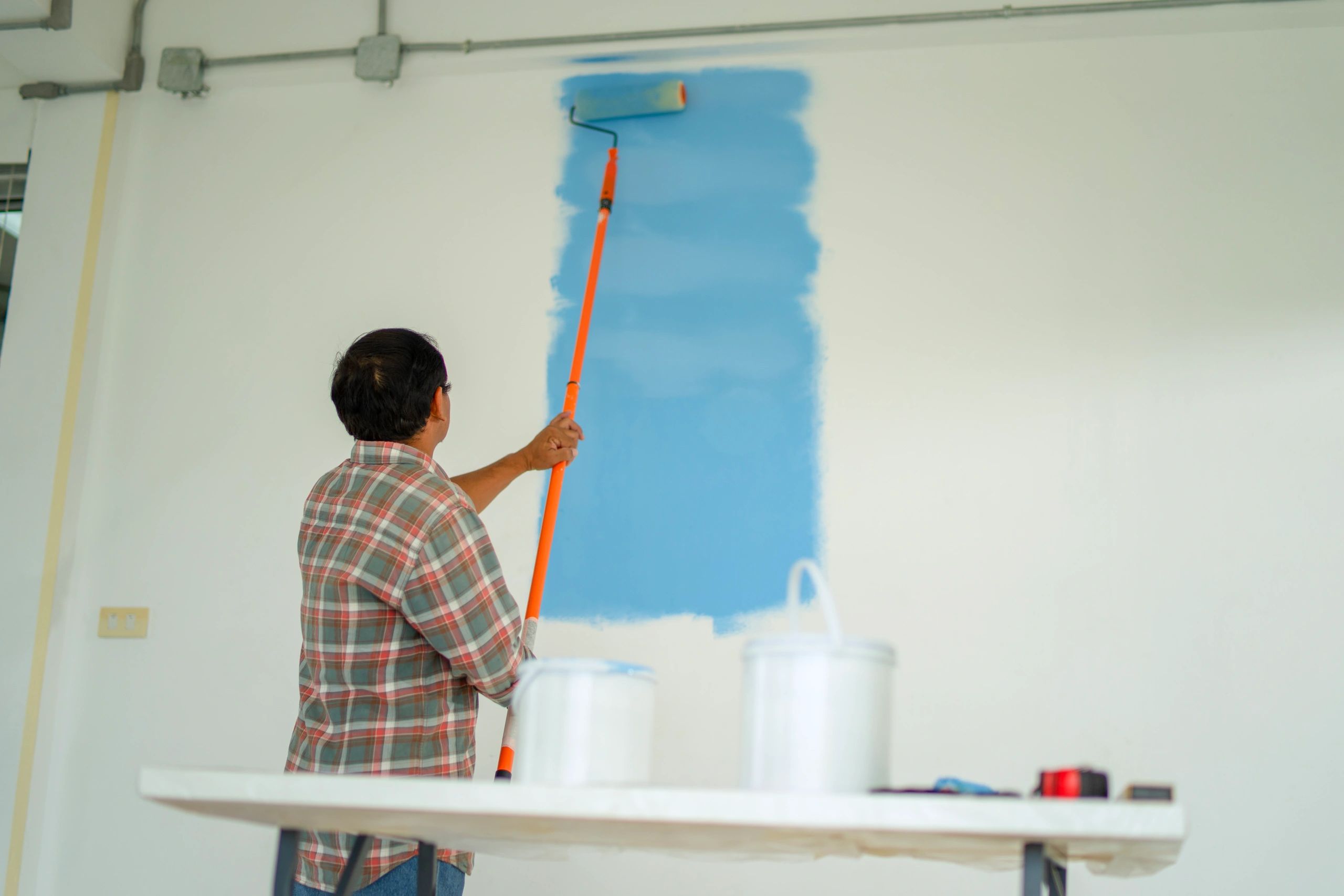Painter applying paint with roller for smooth coverage